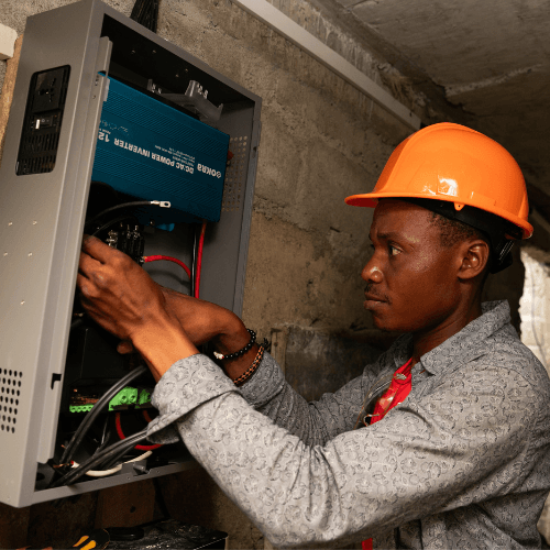a technician wearing an orange hard hat installs electrical wiring inside a power control unit.