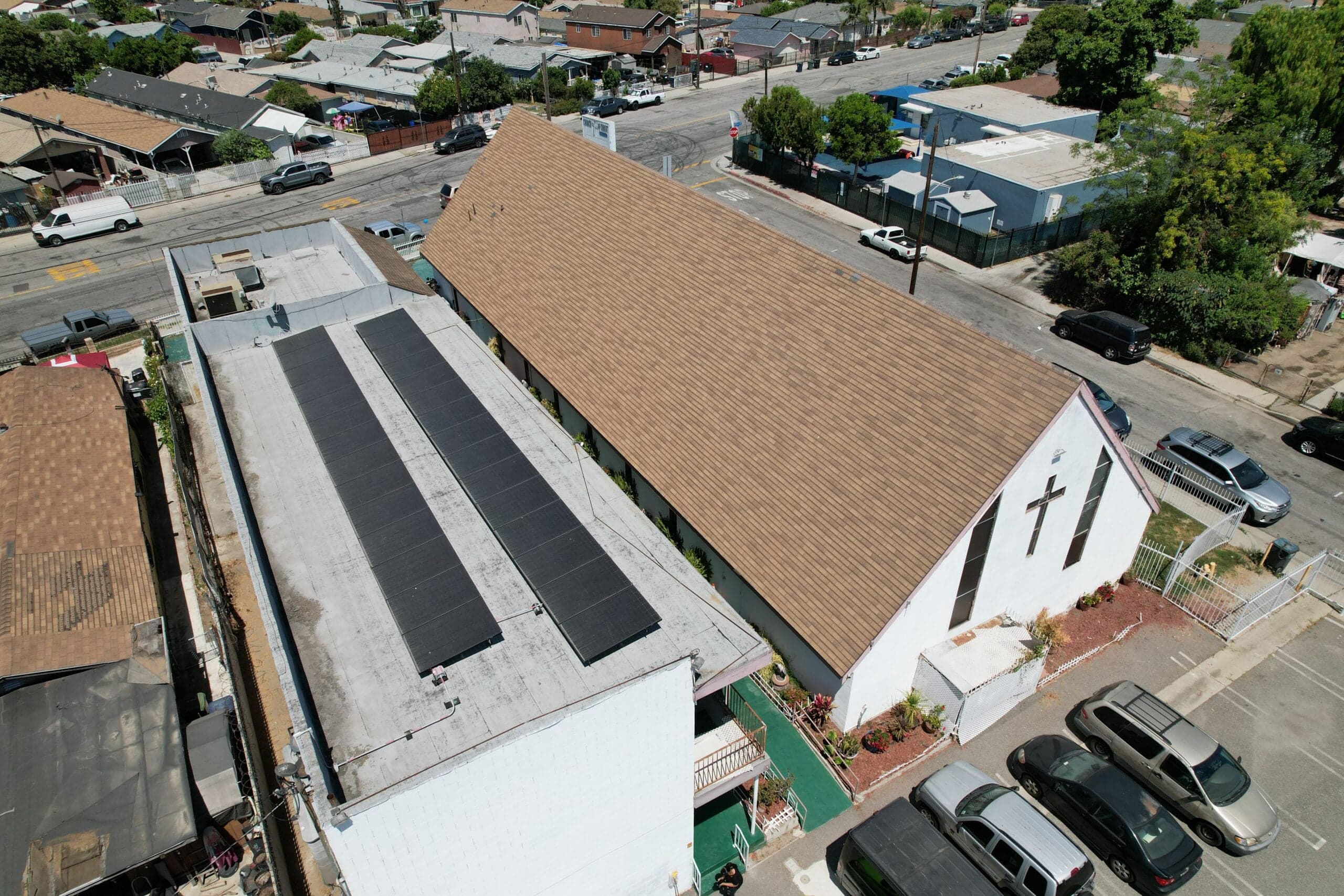 aerial view of a church and adjacent building with rooftop solar panels installed in a residential neighborhood.