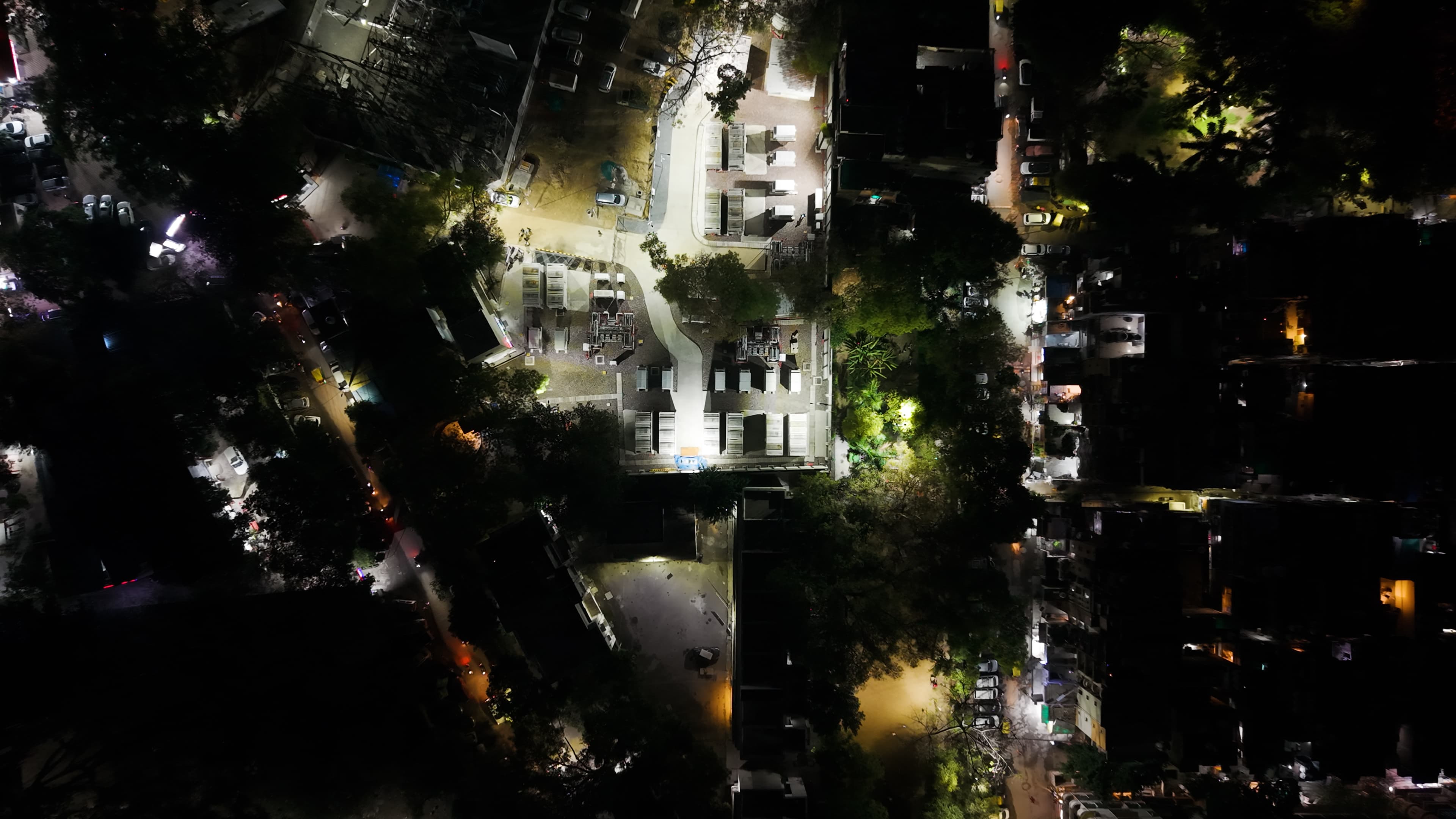 aerial nighttime view of a battery energy storage facility illuminated within a dense urban neighborhood.